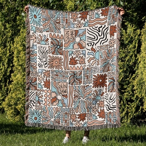 Detail of woven bohemian camping blanket with sun motifs and colorful tassel edges
