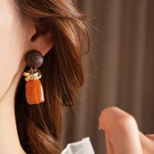 Detail of vintage wooden and amber resin geometric earrings worn on model's ear