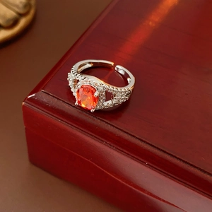 Close-up of sparkling oval orange gemstone ring with zircon pavé on a wooden stand