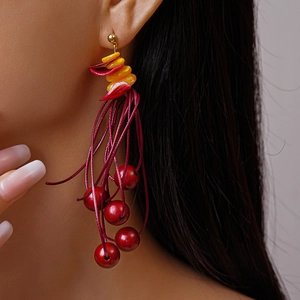 Detail of bohemian red tassel earrings with golden beads and shell-like layered petals