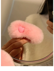 Close-up of a plush pink heart hair clip showing soft texture and glossy center detail