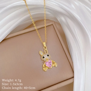 Close-up of golden bunny pendant necklace with pink heart gem on silk background