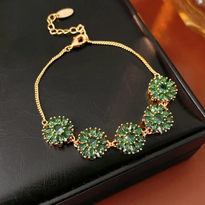 Close-up of vintage golden bracelet with green zircon flowers on black leather box