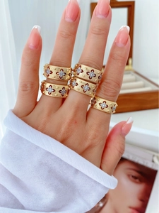 Close-up of gold rings with brushed texture and star motifs on a wooden jewelry box