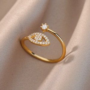Macro shot of gold adjustable Evil Eye ring with star charm on champagne satin fabric