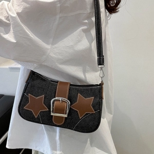 Detail of denim crossbody bag with brown leather stars and metallic buckle on model