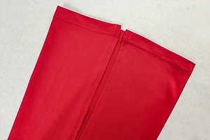 Detailed close-up of double-stitched hem and high-quality red fabric of long sleeve dress