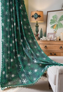 Close-up of green Christmas curtains with white snowflake patterns and elegant tassels