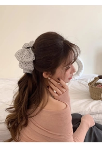 Detailed view of a white polka dot chiffon hair scrunchie styled in a ponytail
