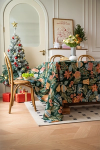 Detail of dark green Christmas tablecloth with woven bells and festive patterns in cozy setting