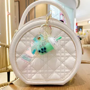 Cute bubble tea cat keychain with green liquid and strap hanging on a stylish white bag