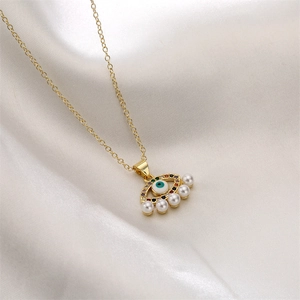 Detail view of gold Evil Eye pendant with blue zircon, colorful stones and hanging pearls