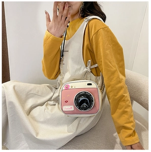 Close-up of creative camera-shaped crossbody bag with pink accents and chain strap
