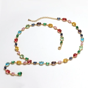 Macro detail of gold chain necklace featuring multi-colored oval cut crystal gemstones