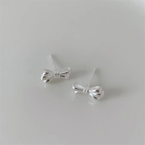 Detailed close-up of a pair of minimalist silver bow earrings with polished finish