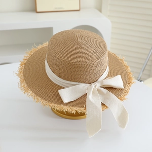 Close-up of raffia sun hat with raw edges and creamy white bow ribbon detail