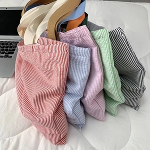 Macro detail of striped canvas tote bags in five vibrant colors with woven handles