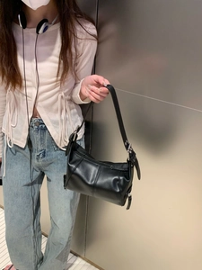 Detail view of a black leather shoulder bag with silver hardware and chic stitching