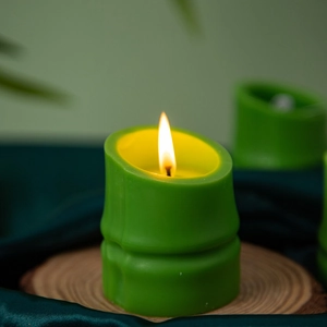 Macro detail of a green bamboo-shaped scented candle on a natural wood base