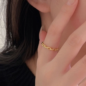 Close-up of a minimalist gold chain link ring worn on the finger with a soft focus background