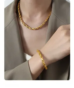 Detail of twisted rope gold-plated necklace and bracelet set on a chic blazer model
