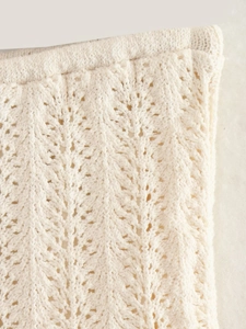 Dettaglio macro del tessuto a maglia traforato bianco crema con motivi a onde e texture