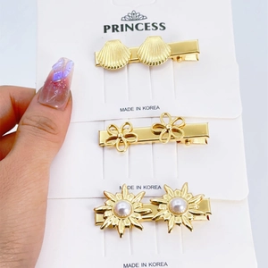 Close-up of gold stainless steel hair clips featuring shells, flowers, and pearl sunburst