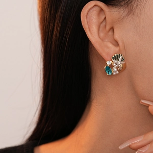 Détail de boucles d'oreilles étoile de mer dorées avec pierre bleue et perles