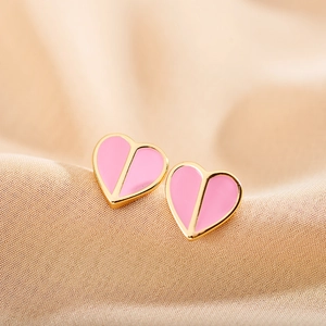 Detailed view of pink enamel heart earrings with gold trim on champagne silk fabric