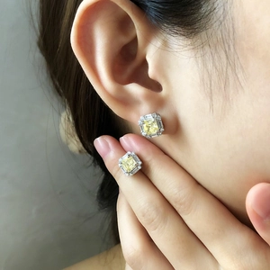 Detail view of square cut yellow gemstone stud earrings with halo diamond setting