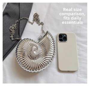 Detailed view of silver shell-shaped evening bag with metallic texture and chain strap