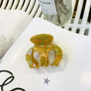 Elegant amber marble acetate hair claw clip on a white magazine for women's styling