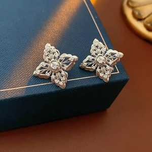 Macro detail of silver flower stud earrings with zircon crystals on blue jewelry box