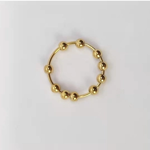 Detail of gold rotatable beads on a stainless steel anti-anxiety spinner ring