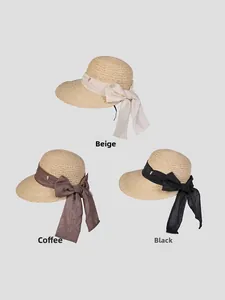 Détail de chapeau de soleil en raphia avec nœud en soie élégant et logo en métal coloré