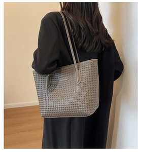 Brown woven tote bag with slim shoulder strap shown on model in natural indoor lighting