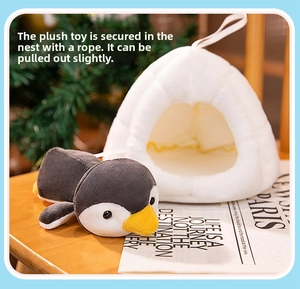 Close-up of cute penguin plush toy sitting in a soft white fabric nest on a wooden table