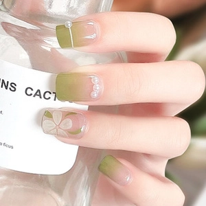 Detail of green gradient press-on nails with white 3D flowers and pearl accents