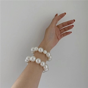 Elegant large pearl elastic hair ties and bracelets set worn on a woman's wrist