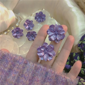 Close-up of elegant purple 3D flower stud earrings with delicate pearl finish and silver needles