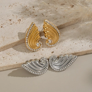 Elegant gold and silver rhinestone wing stud earrings displayed on natural stone