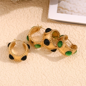 Macro detail of 18K gold plated earrings with beaded edges and round gemstone inlays