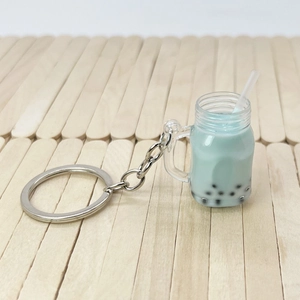 Close-up of creative mint green bubble tea keychain with pearls on wooden background