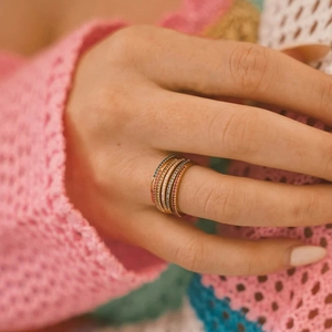 Close-up of stacked gold-plated eternity rings with vibrant colorful zircon stones