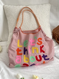 Detail of colorful chenille embroidery on pink canvas tote bag with woven strap