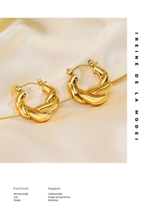 Détail macro de boucles d'oreilles créoles torsadées plaquées or 18 carats sur soie