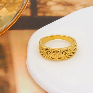 Macro shot of gold-finished ring with intricate hollow floral patterns on a display stand