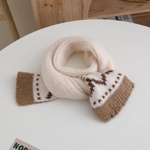 Detailed view of beige knitted scarf with brown Nordic pattern on a white table