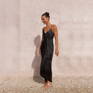 Détail d'une robe longue en satin noir avec nœud à la taille et fente latérale chic