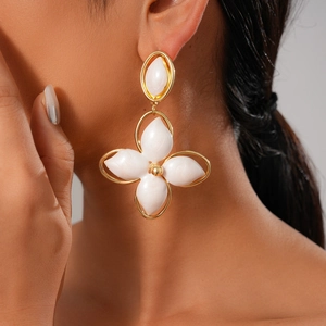 Detail of model wearing vintage golden oval cutout flower earrings with white enamel petals